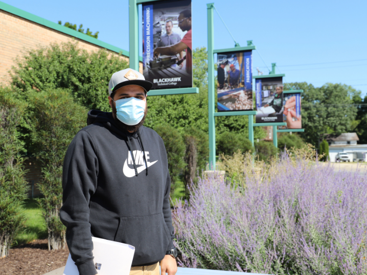 student standing outside of AMTC wearing hat and mask